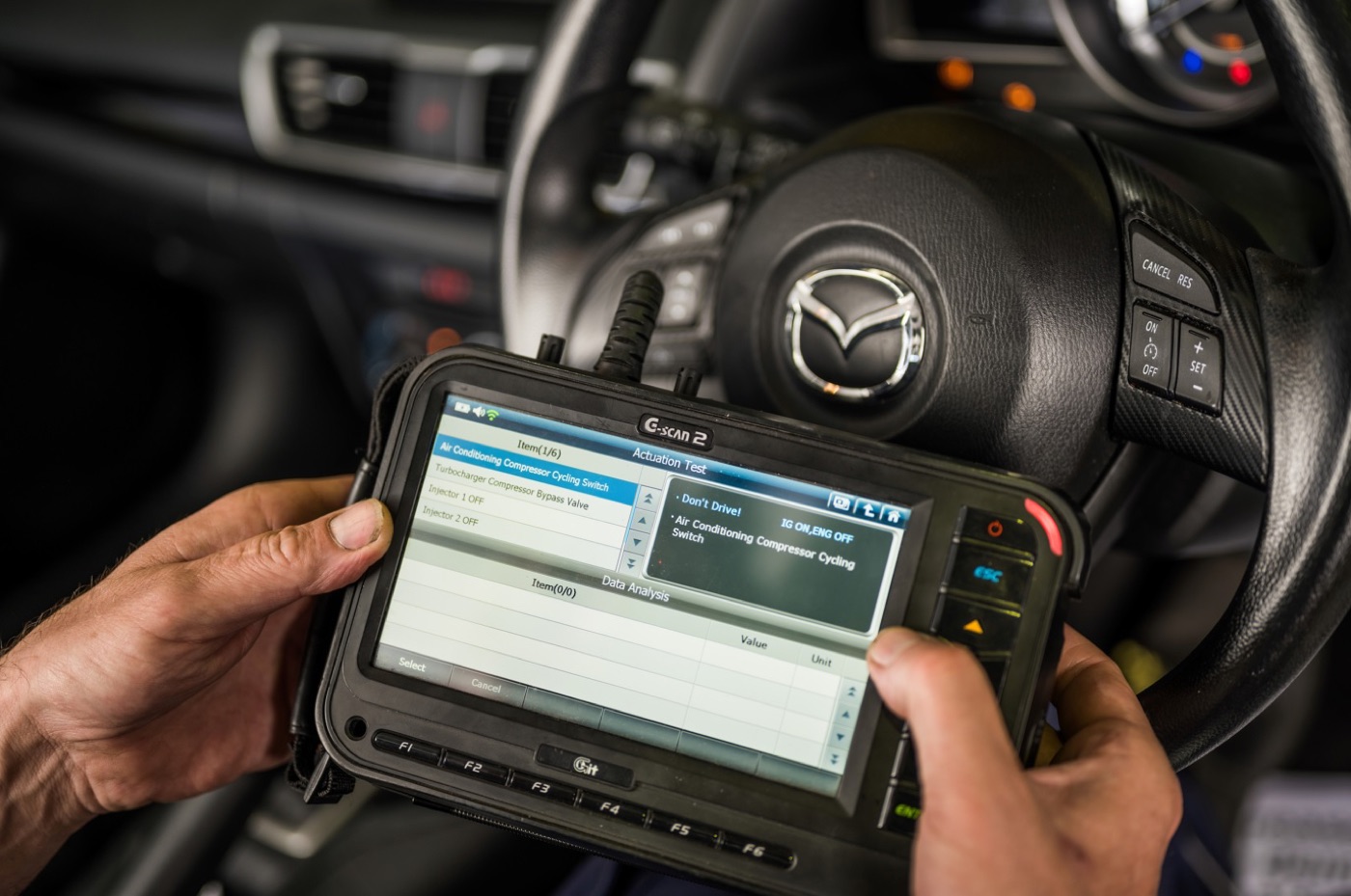 A diagnostic scan tool being used from the driver's seat during a service